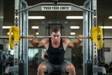a man is squating in a smith machine in a gym