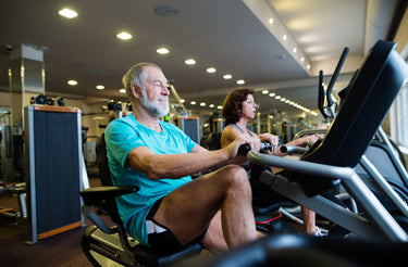 two people riding recumbent exercise bikes in a gym